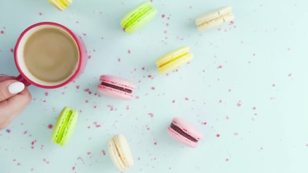 Draufsicht auf bunte Kekse, französische Macarons und eine Tasse Kaffee auf pastellblauem Hintergrund mit schön verstreuten Konfetti — Stockvideo