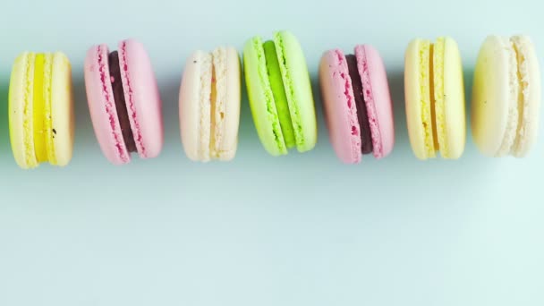Bovenaanzicht van veelkleurige Franse Macarons koekjes op een pastelblauwe achtergrond — Stockvideo