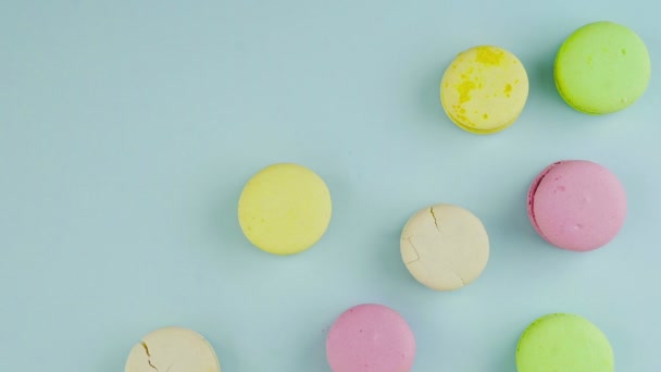 Vista superior de biscoitos multicoloridos Macarons franceses em um fundo azul pastel com confetes lindamente espalhados — Vídeo de Stock