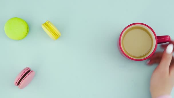 Верхній вид різнокольорових французьких печива Macarons і чашечка кави на пастельному синьому тлі. — стокове відео