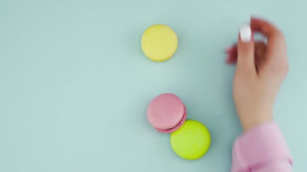 Vue de dessus des biscuits Macarons français multicolores et une tasse de café sur un fond bleu pastel — Video