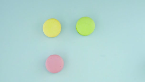 Vue de dessus des biscuits Macarons français multicolores et une tasse de café sur un fond bleu pastel — Video