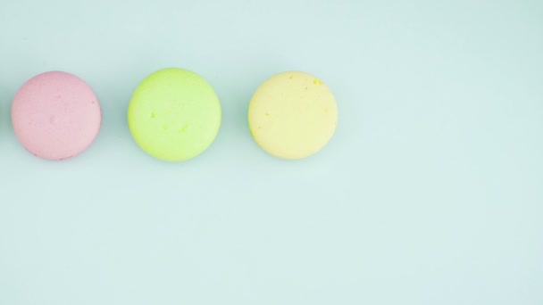 Horní pohled na pestrobarevné francouzské Macarons cookies a šálek kávy na pastelově modrém pozadí — Stock video
