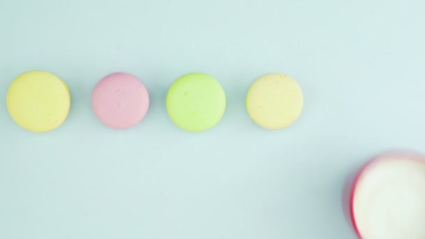 Vue de dessus des biscuits Macarons français multicolores et une tasse de café sur un fond bleu pastel — Video