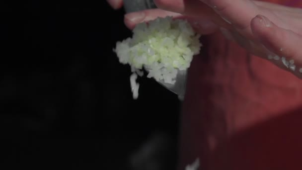 Detailní záběr pánských rukou jemně nasekané cibule jsou vrženy z nože do pánve na smažení. Koncept vaření — Stock video