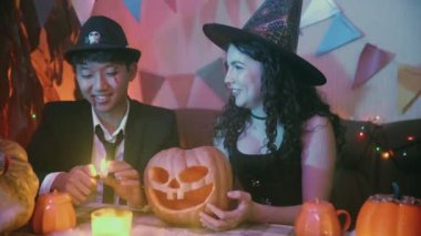 Adam balkabağının içine bir mum koyar ve balkabağı parlamaya başlar. Bir grup arkadaş Cadılar Bayramı 'nı gülerek ve sohbet ederek kutluyor..