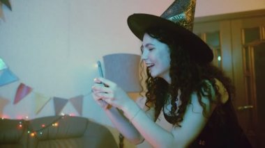 Bir kız Cadılar Bayramı 'nda fotoğraf çeker ya da arkadaşının telefonunda fotoğraf çeker.