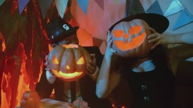 Cadılar Bayramı 'nda kameranın önünde Jack-o-Lantern pozu veren ürkütücü kostümlü bir adam ve bir kız.