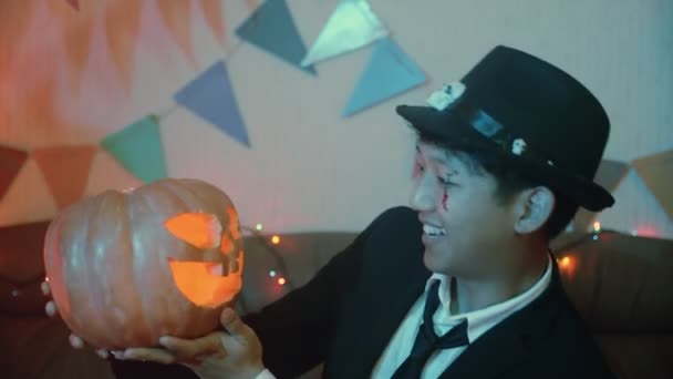 Um cara com um traje assustador com uma Jack-o-lanterna posa na frente da câmera no Halloween — Vídeo de Stock