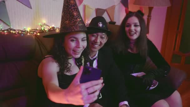 Μια ομάδα φίλων με ανατριχιαστικά κοστούμια, επικοινωνούν μέσω video link μέσω τηλεφώνου και γελάνε στο Halloween — Αρχείο Βίντεο