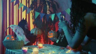 Bir kız Cadılar Bayramı 'nda fotoğraf çeker ya da arkadaşının telefonunda fotoğraf çeker.