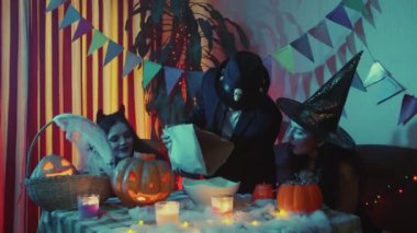 Adam tabağa şeker koyuyor. Arkadaşlar Cadılar Bayramı 'nı gülerek ve sohbet ederek kutlarlar.