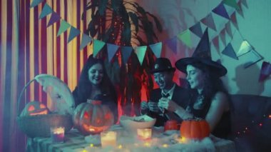 Adam tabağa şeker koyuyor. Arkadaşlar Cadılar Bayramı 'nı gülerek ve sohbet ederek kutlarlar.