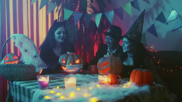 Eine Gruppe von Freunden feiert Halloween, setzt eine medizinische Maske auf eine Jack-o-Laterne und lacht laut. Nahaufnahme — Stockvideo