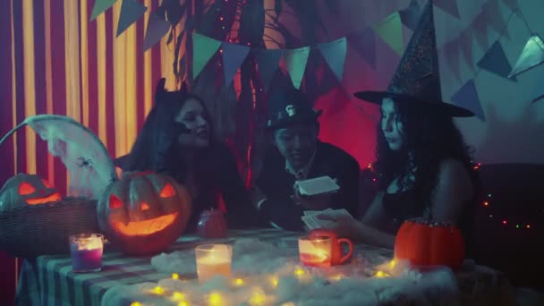 Eine Gruppe von Freunden tippt an Halloween auf Karten. Wahrsagerei auf Karten — Stockvideo