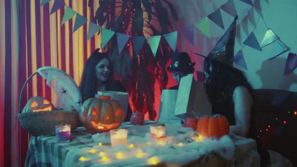 Eine Gruppe von Freunden wird herausfinden, wie viele Bonbons sich in Papiertüten befinden. Freunde feiern Halloween, indem sie gemeinsam lachen und plaudern — Stockvideo