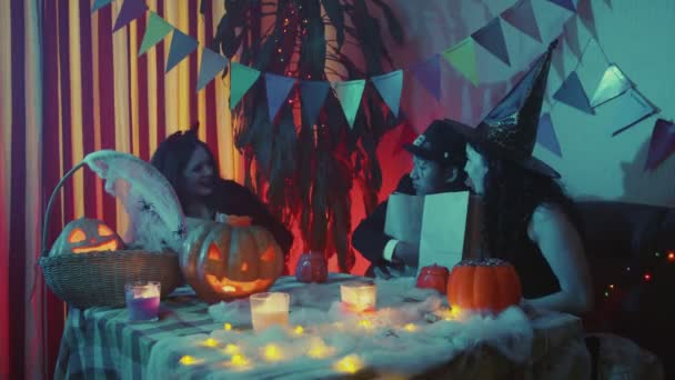 Grupa przyjaciół dowie się, ile cukierków jest w papierowych torbach. Przyjaciele świętują Halloween śmiejąc się i rozmawiając razem — Wideo stockowe