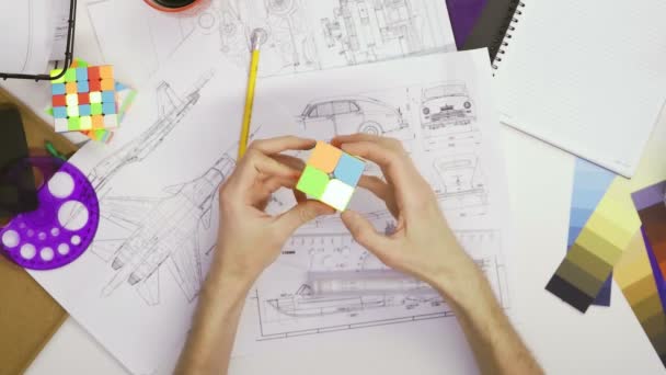 Top view the hands of a male designer solve a puzzle with a Rubiks cube. Cube puzzle, a puzzle game. — Stock Video