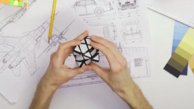 Üst görünüm erkek tasarımcının elleri bir Rubiks küpüyle bulmacayı çözer. Küp bulmacası, bir bulmaca oyunu.