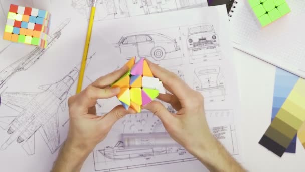 Von oben lösen die Hände eines männlichen Designers ein Puzzle mit einem Rubiks-Würfel. Cube Puzzle, ein Puzzlespiel. — Stockvideo