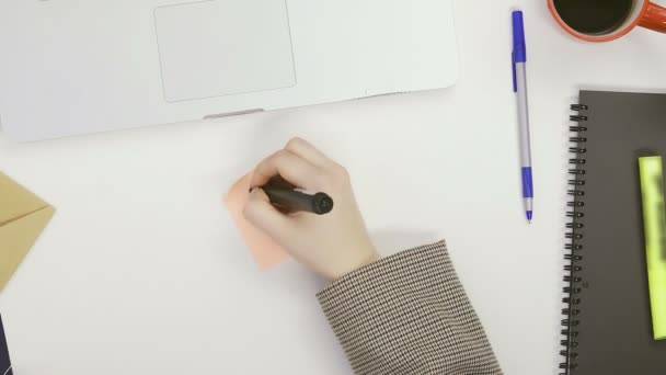 Top view een vrouw schrijft brieven op memory stickers met een marker, zittend aan een tafel in een lichte kamer — Stockvideo