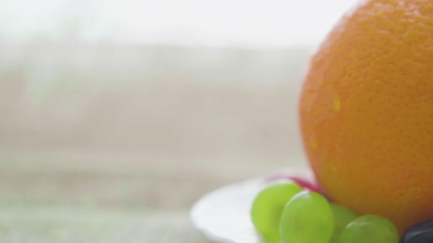 Sinaasappel en druiven op een bord, close-up — Stockvideo