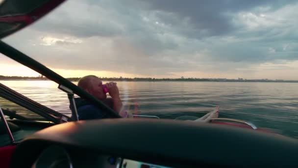 Хлопець і дівчина сидять на моторному човні, розмовляючи і спостерігаючи за заходом сонця. Романтична атмосфера . — стокове відео