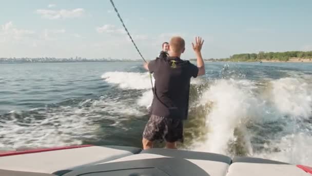 La fille est une surfeuse, chevauchant un wakeboard. Un wakeboarder expérimenté aide une fille — Video