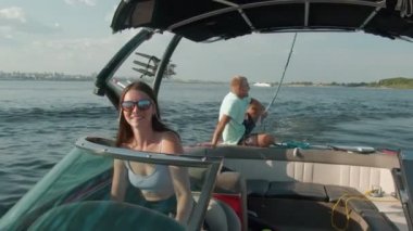 Bir kadın motorlu tekne kullanıyor ve bir erkek arka planda oturuyor ve temiz havanın tadını çıkarıyor.