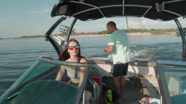 Une femme conduit un bateau à moteur, un homme en arrière-plan — Video