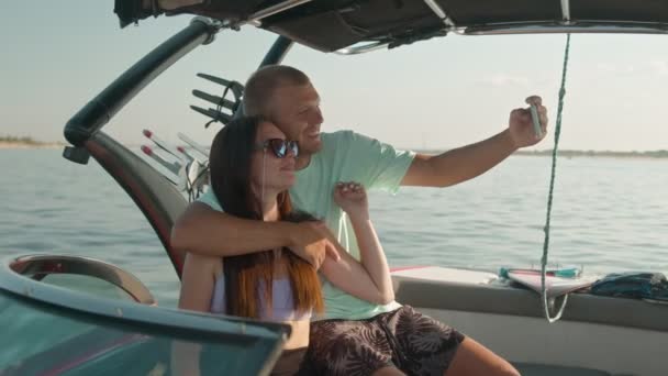 Muž a žena sedí v motorovém člunu a fotí — Stock video