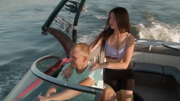 Een man en een vrouw zitten in een motorboot, kijken elkaar aan en praten. — Stockvideo