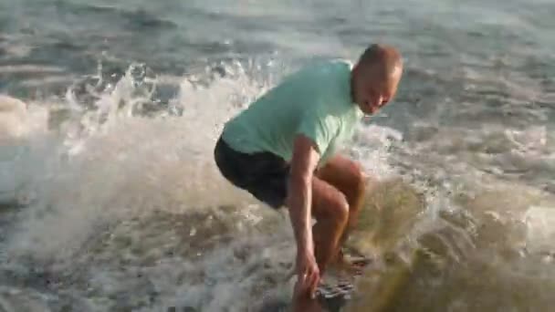 Серфер стрибає на веслувальну дошку. Досвідчений пансіонат розпилює воду в камеру.. — стокове відео