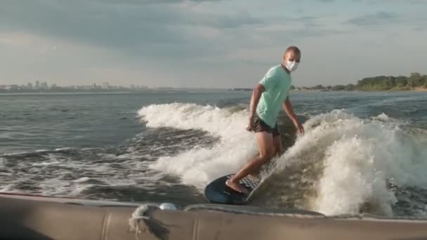 Een surfer die op een wakeboard springt in een masker. Een ervaren wakeboarder spat water in de camera. — Stockvideo