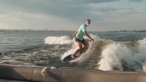 Ein Surfer springt mit Maske auf einem Wakeboard. Ein erfahrener Wakeboarder spritzt Wassertropfen in die Kamera. — Stockvideo