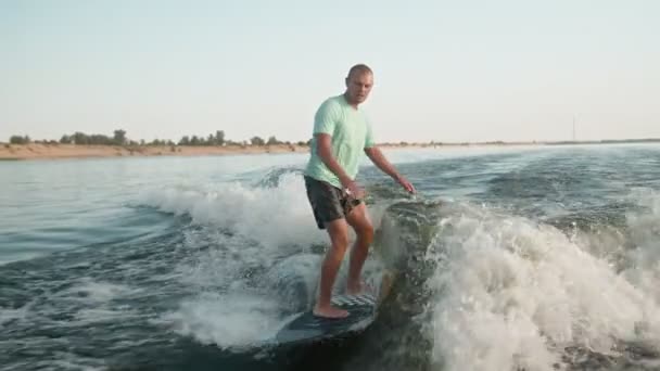 Un surfista saltando sobre un wakeboard. Un experimentado wakeboarder rocía agua en la cámara. — Vídeos de Stock