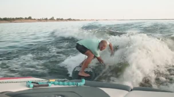 Surfař skákající na wakeboardu. Zkušený wakeboarder rozstřikuje do kamery kapky vody. — Stock video