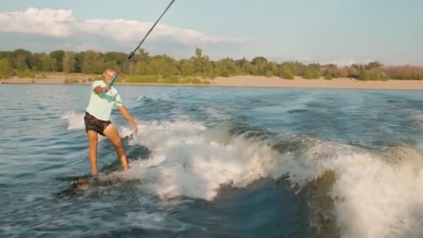 Ein Surfer springt auf einem Wakeboard. Ein erfahrener Wakeboarder sprüht Wassertropfen in die Kamera. — Stockvideo