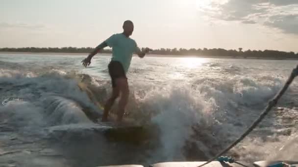 一个冲浪运动员跳到了一块滑板上.一位经验丰富的觉醒者向相机里喷射水滴. — 图库视频影像