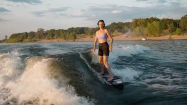 Wakeboard 'a atlayan dişi bir sörfçü. Deneyimli bir wakeboardcu kameraya su damlatıyor..