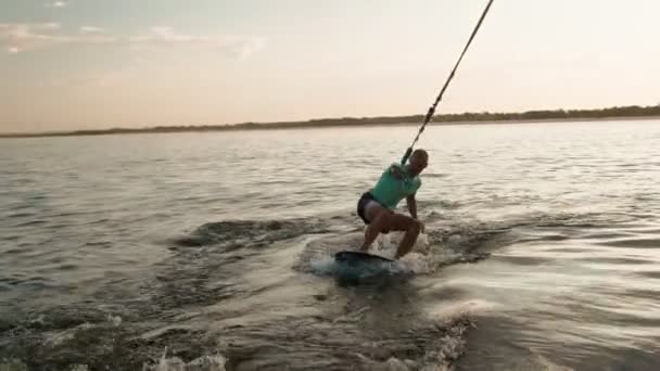 Surfař skákající na wakeboardu. Zkušený wakeboarder rozstřikuje do kamery kapky vody. — Stock video