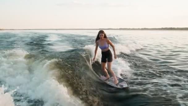Surfařka skákající na wakeboardu. Zkušený wakeboardista cáká vodu kapky do kamery. — Stock video