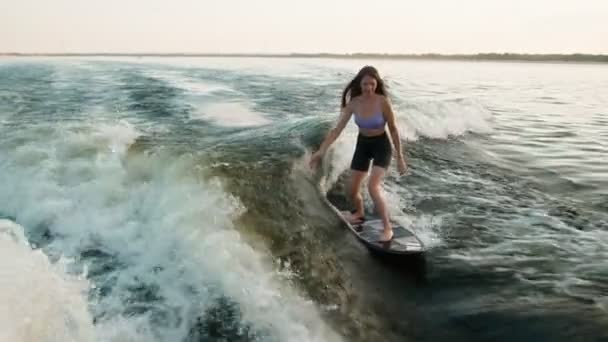 Surfařka skákající na wakeboardu. Zkušený wakeboardista cáká vodu kapky do kamery. — Stock video