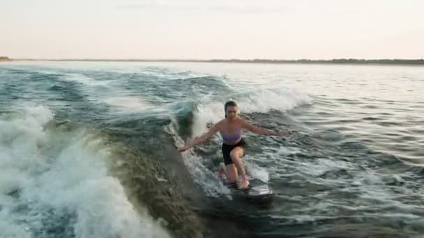 Surfařka skákající na wakeboardu. Zkušený wakeboardista cáká vodu kapky do kamery. — Stock video