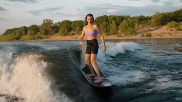 一个女冲浪者跳到了一块滑板上.一个有经验的觉醒者把水滴到相机里. — 图库视频影像