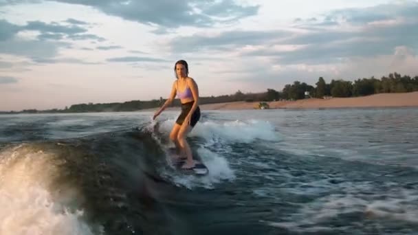 Een vrouwelijke surfer springt op een wakeboard. Een ervaren wakeboarder spat water in de camera. — Stockvideo