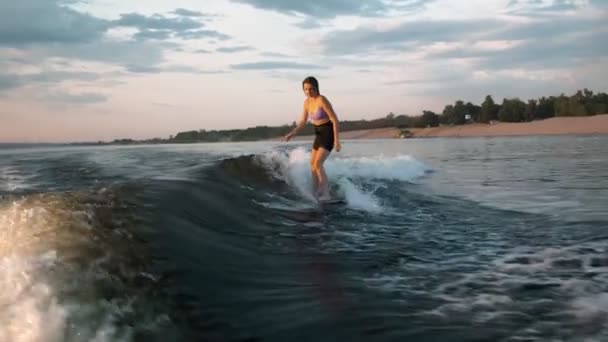 ウェイクボードに飛び乗る女性サーファー。経験豊富なウェイクボーダーは、カメラに水が落ちる. — ストック動画