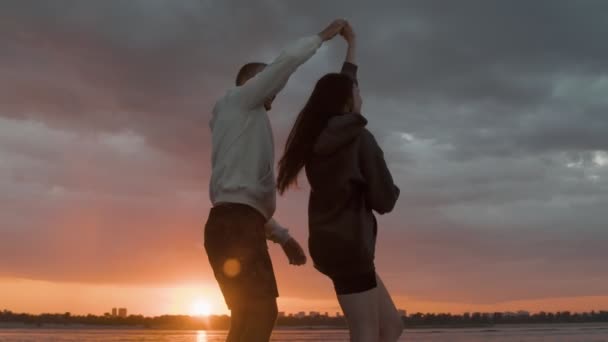 Un tipo rodea a una chica en una lancha motora contra el fondo de la puesta de sol. Ambiente romántico. — Vídeo de stock