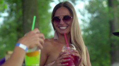 Kumsalda güneşlenen ve kokteyl içen iki genç kadın.