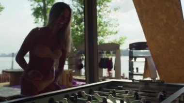 Masa futbolu oynayan ya da minyatür oyuncularla mayo giyen kadınlar.